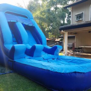 A blue inflatable water slide set up in a backyard.