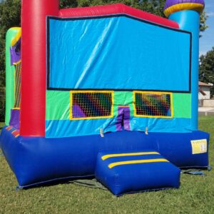 Colorful inflatable bounce house set up on green grass under a clear sky.