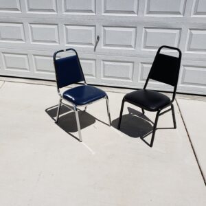 Two folding chairs, one blue and one black, sitting on concrete.