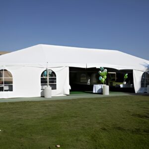 Large white event tent set up on a grassy field under clear blue sky.